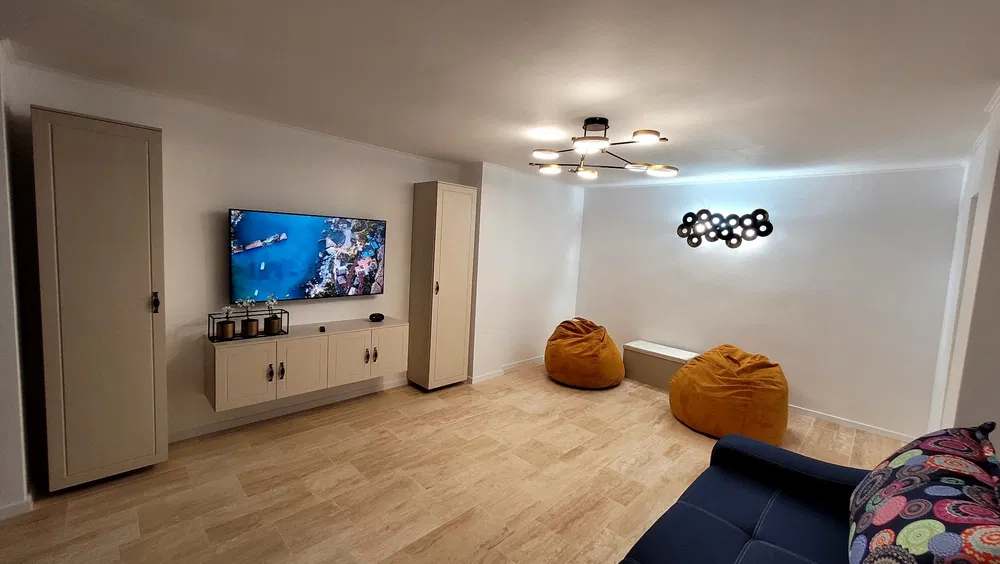 A living room with a flat screen TV, a cabinet, and a window