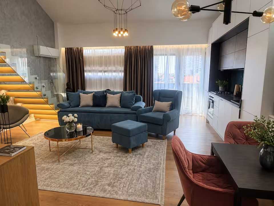 O cameră de zi cu o canapea albastră și un scaun — apartament în Oradea
