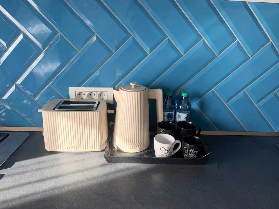 O bucătărie cu o mașină de cafea, un fierbător de ceai și sticle de apă — apartament în Oradea
