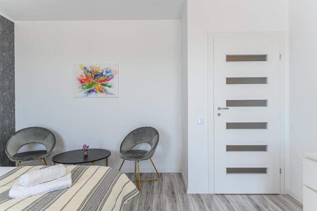 O cameră cu un pat, un scaun și o pictură pe perete — apartament în Brașov