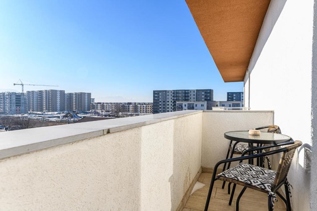 O vedere a unui balcon cu scaune și o masă — apartament în Brașov