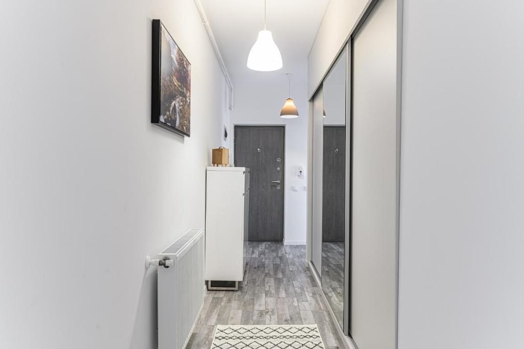O cameră mică cu o ușă albă și o oglindă — apartament în Brașov