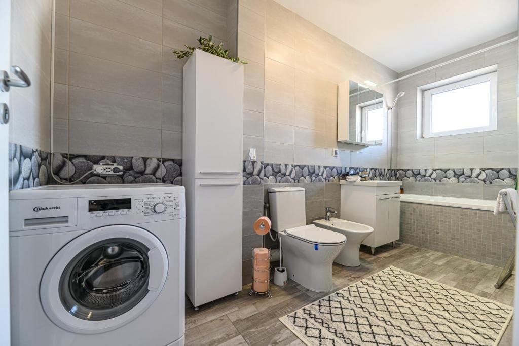 O baie cu toaletă, chiuvetă și mașină de spălat — apartament în Brașov