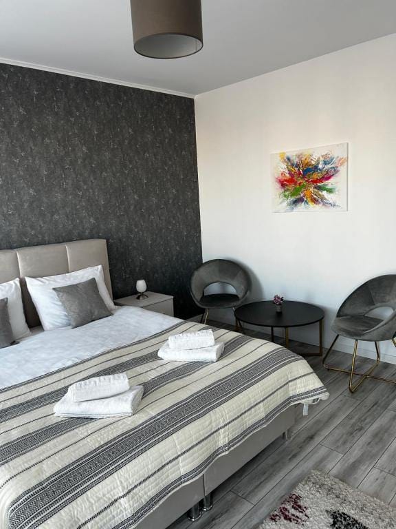 O cameră cu un pat, un scaun și o imagine pe perete — apartament în Brașov