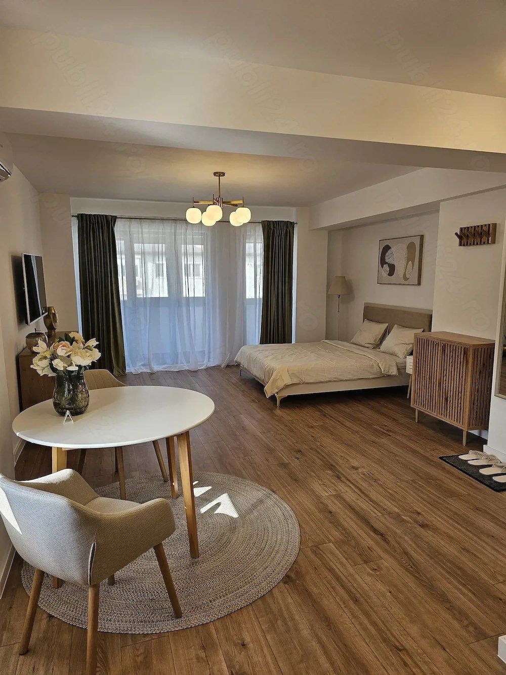 A bedroom with a bed, a table, and a window