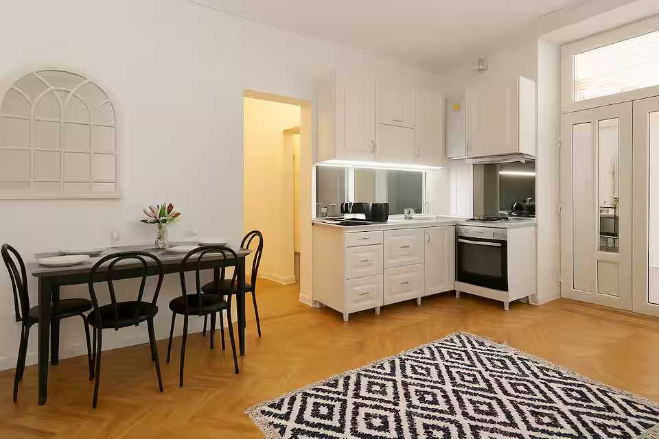 O bucătărie cu dulapuri albe și o masă — apartament în Oradea