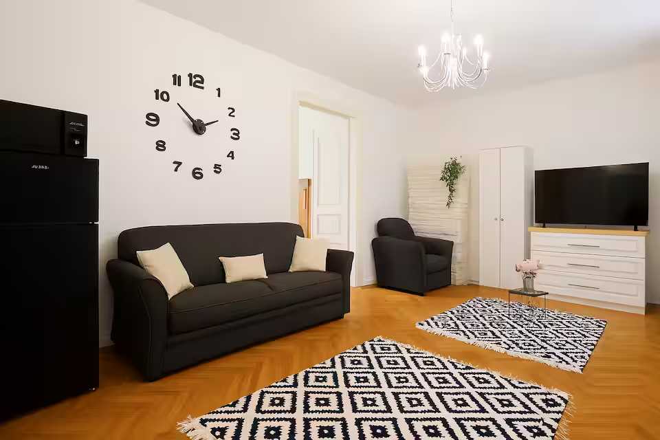 O camera de zi cu canapea, scaun si ceas — apartament în Oradea