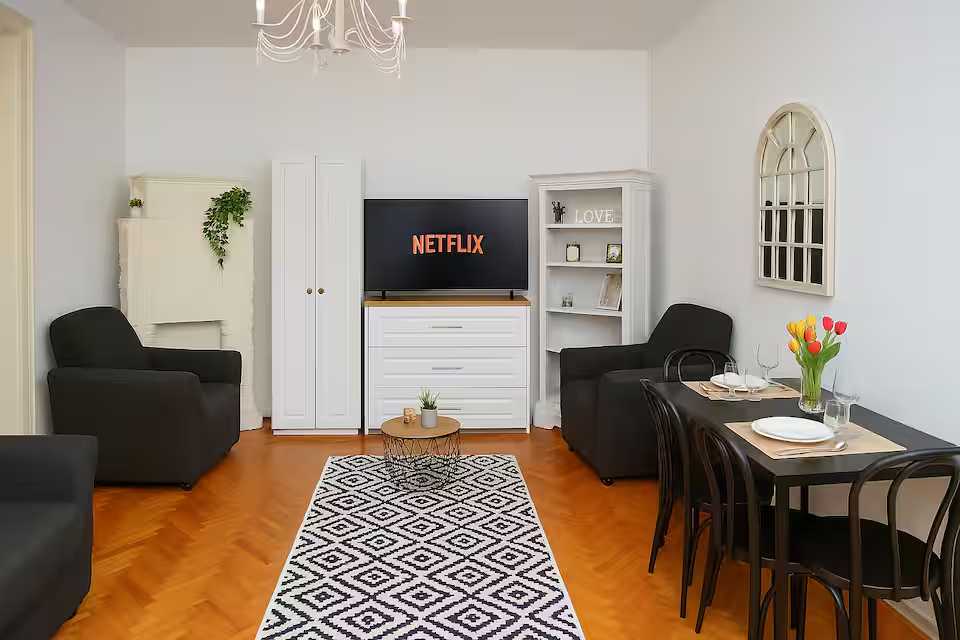 O camera de zi cu canapea neagra si un dulap alb — apartament în Oradea