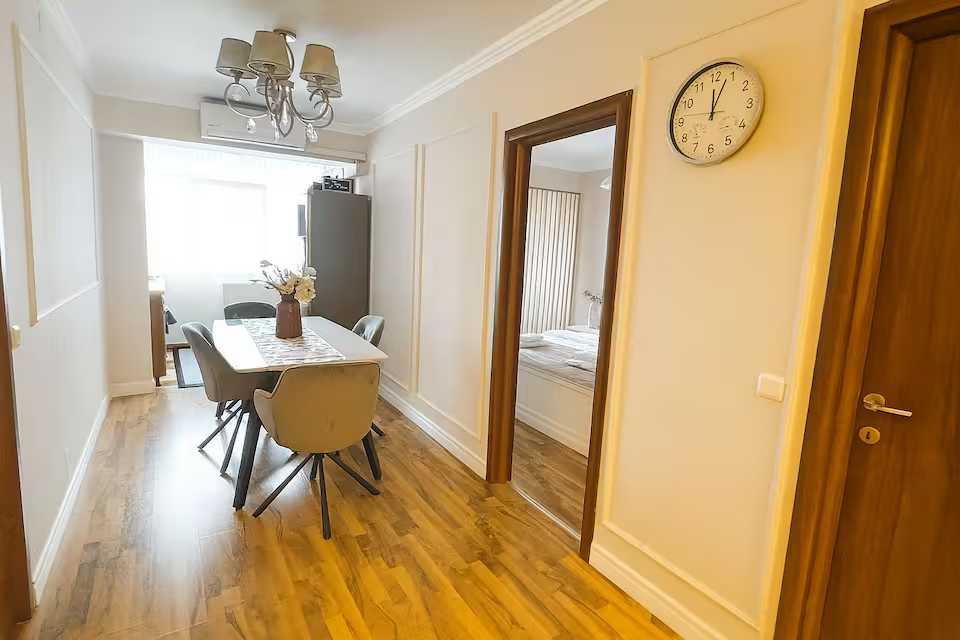 O cameră mică, curată și bine luminată, cu o masă și scaune — apartament în Oradea