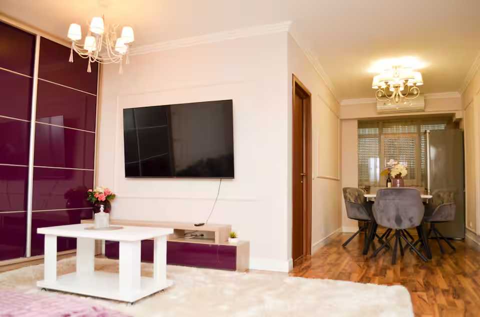 O cameră de zi cu televizor cu ecran plat și o masă — apartament în Oradea